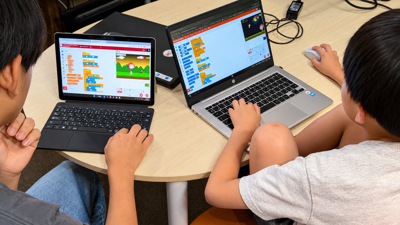 Scratchでプログラムを試しながら制作する子どもの手元とパソコン